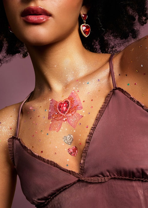 Rococo Hearts temporary tattoos on chest with glitter and heart gems. Pink bow with ruby heart centerpiece.